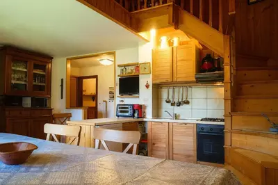 a kitchen with wooden cabinets and a table with chairs at Appartamento Pepe by Sunhome Fiemme in Castello di Fiemme