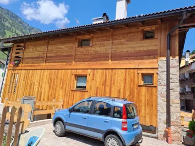 a blue car parked in front of a wooden building at Tabia' Cemin in Predazzo