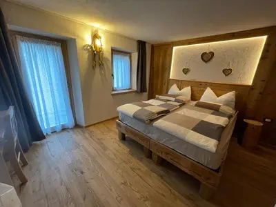 a bedroom with a large bed with a wooden headboard at LA POESIA DOLOMITI APARTMENTS in Rivamonte