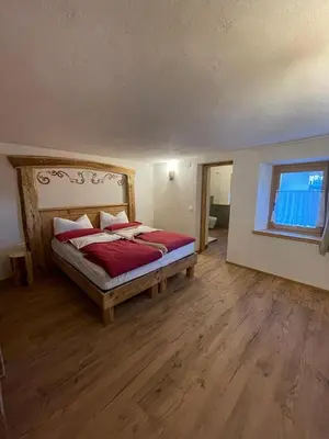 a bedroom with a bed with red sheets and a window at LA POESIA DOLOMITI APARTMENTS in Rivamonte