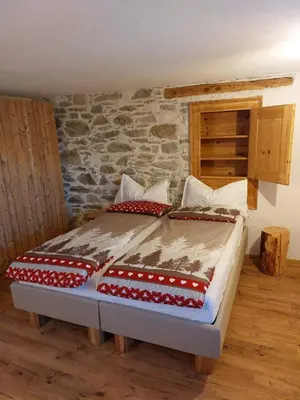 a bed in a room with a stone wall at LA POESIA DOLOMITI APARTMENTS in Rivamonte