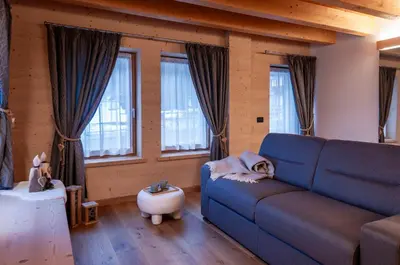 a living room with a blue couch and windows at Antico Borgo Palue in Sottoguda