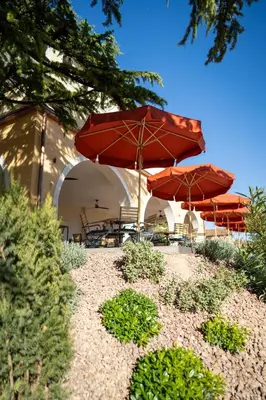 a patio with red umbrellas and tables and chairs at Castel Sallegg Suites Adults only in Caldaro