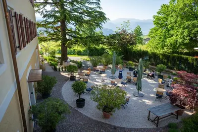 a courtyard with tables and chairs and trees at Castel Sallegg Suites Adults only in Caldaro