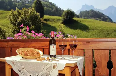 a table with two glasses of wine and a bowl of food at Müllerhof in Kastelruth
