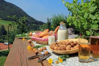 a picnic table with a basket of food and milk at Müllerhof in Kastelruth
