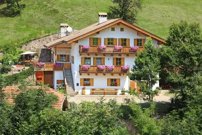 a house with a balcony and flowers on it at Müllerhof in Kastelruth