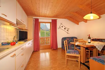 a kitchen with a table and a dining room at Müllerhof in Kastelruth