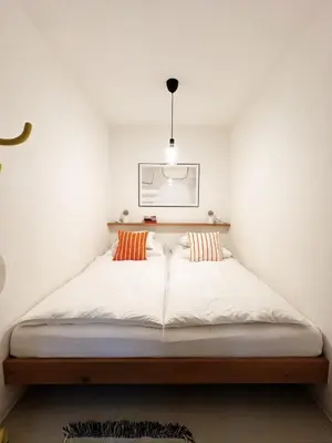 a bedroom with a bed with white sheets and orange pillows at Late Checkout Merano - 3 Zimmer, Sonnenterrasse, Garage in Merano