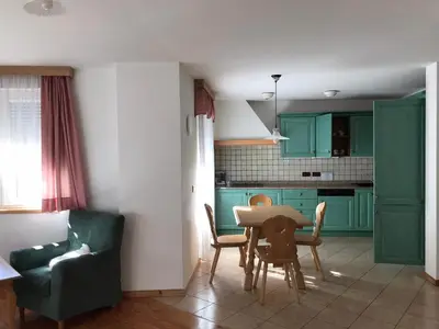 a kitchen with green cabinets and a table and chairs at Appartamenti Residence Rodolon Fontanazzo in Campestrin
