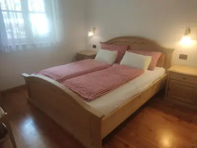 a bedroom with a wooden bed with red and white pillows at Appartamenti Residence Rodolon Fontanazzo in Campestrin