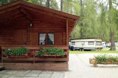 a wooden cabin with two windows and a trailer at International Camping Olympia in Cortina dʼAmpezzo