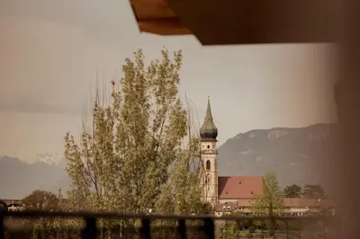 a building with a clock tower with a tree in the foreground at Gutshof Ebner in San Paolo