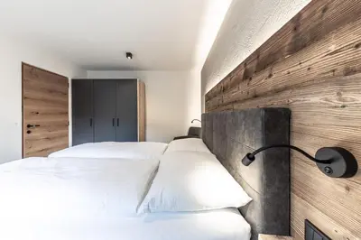 a bedroom with two white beds and a wooden wall at Moarhof - Apartments and moar in Varna