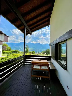 a wooden deck with a table and a view of the mountains at Mountain Chalet Tre Marie in Cavalese