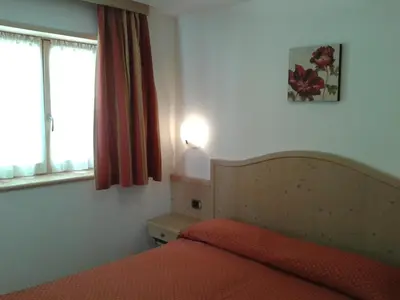 a bedroom with a bed with a orange bedspread and a window at Appartamento da Meto in San Martino di Castrozza