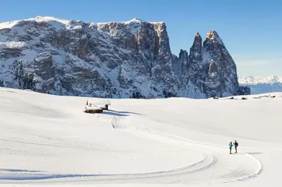 two people walking in the snow with a mountain in the background at Casa Panoràma in the heart of the Dolomites, Moena in Moena