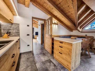 a kitchen with wooden cabinets and a large window at Casa Panoràma in the heart of the Dolomites, Moena in Moena