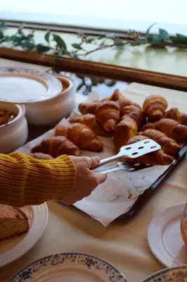 a person holding a pair of tongs over a tray of pastries at Albergo Venezia in Passo Rolle
