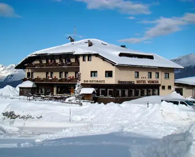 a large building with a snow covered roof at Albergo Venezia in Passo Rolle