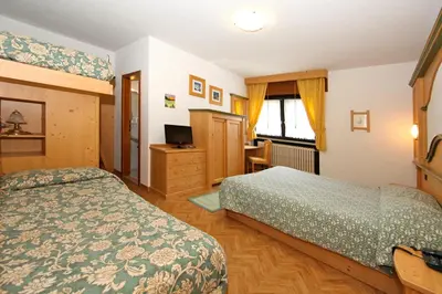 a hotel room with two beds and a television at Albergo Venezia in Passo Rolle