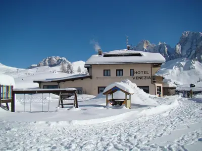 a hotel in the snow with a building at Albergo Venezia in Passo Rolle