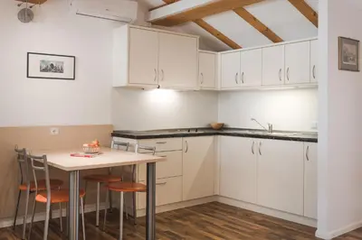 a kitchen with white cabinets and a table with stools at Ansitz Rynnhof in Termeno