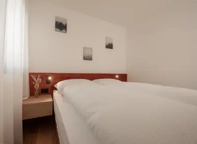 a white bedroom with a white bed and a window at Luxury Penthouse - Between Kronplatz, 3 Peaks Dolomites and Lake Prags in Monguelfo