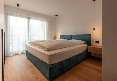 a bedroom with a large bed with a large window at Luxury Penthouse - Between Kronplatz, 3 Peaks Dolomites and Lake Prags in Monguelfo