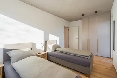 two beds in a room with white walls and wood floors at Ferienhaus Obergfillhof in Missiano