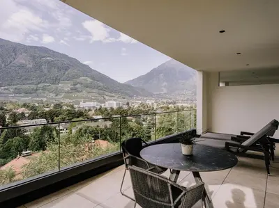 a balcony with a table and chairs and mountains at The Hills in Merano