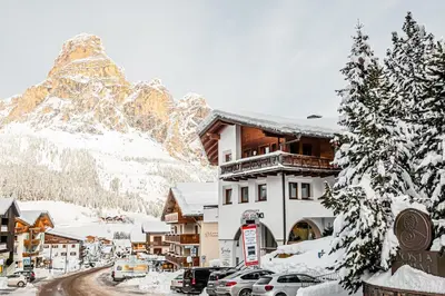 a ski lodge with a mountain in the background at Posta Zirm Residence in Corvara in Badia