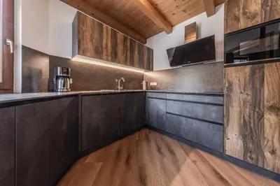 a kitchen with dark wood cabinets and a tv at Posta Zirm Residence in Corvara in Badia