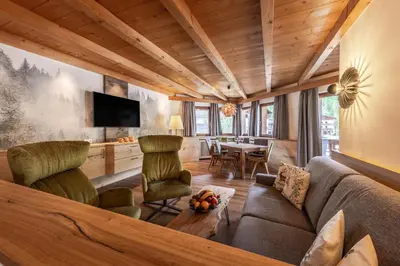 a living room with a couch and chairs and a table at Posta Zirm Residence in Corvara in Badia
