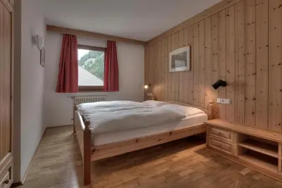 a bedroom with a bed and a window at Posta Zirm Residence in Corvara in Badia