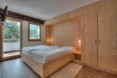 a bedroom with a large bed and a window at Posta Zirm Residence in Corvara in Badia