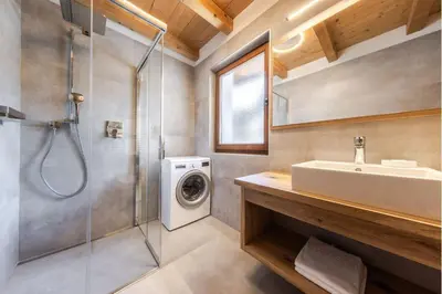 a bathroom with a sink and a washing machine at Posta Zirm Residence in Corvara in Badia