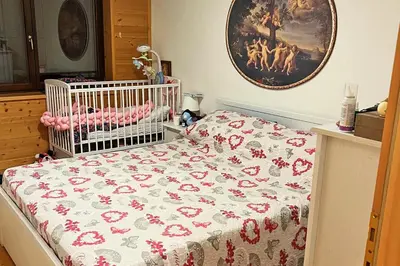 a crib with a blanket on it in a bedroom at Chalet Erika: che vista! in San Martino di Castrozza