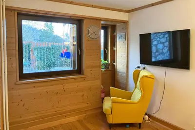 a living room with a yellow chair and a television at Chalet Erika: che vista! in San Martino di Castrozza