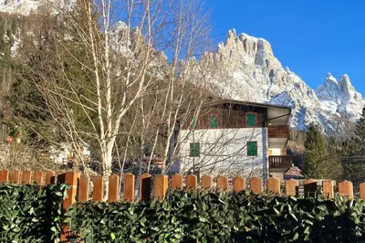 a fence in front of a building in front of a mountain at Chalet Erika: che vista! in San Martino di Castrozza