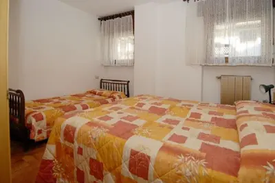 a bedroom with two beds and two windows at CASA PINUCCIA APPARTAMENTO EST in Predazzo