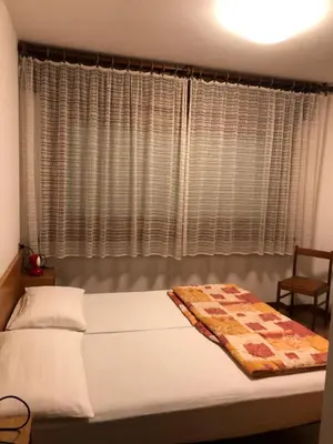 a bedroom with a bed and a window with curtains at CASA PINUCCIA APPARTAMENTO EST in Predazzo