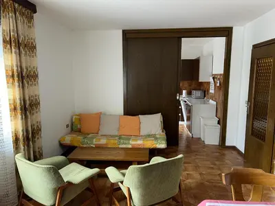 a living room with a couch and chairs and a kitchen at CASA PINUCCIA APPARTAMENTO EST in Predazzo