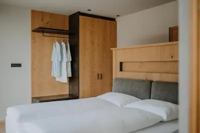 a bedroom with a white bed and a wooden wall at Stollhof in Lagundo
