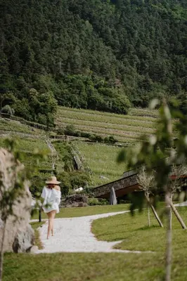 a woman walking down a path with a mountain at Stollhof in Lagundo