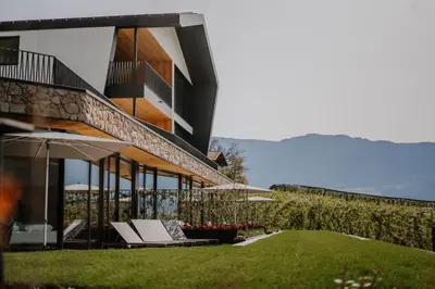 a building with chairs and umbrellas in the grass at Stollhof in Lagundo