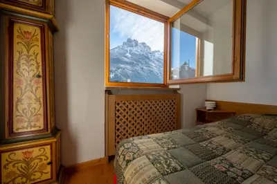 a bedroom with a large window with a mountain view at Cesa Azola in Vigo di Fassa