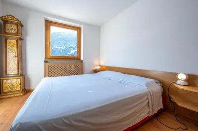 a bedroom with a white bed and a window at Cesa Azola in Vigo di Fassa