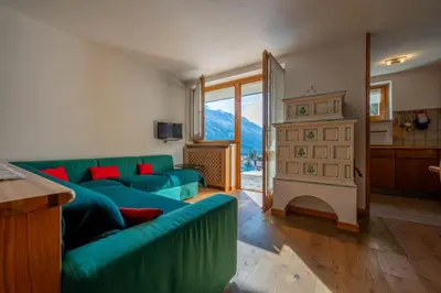 a living room with a green couch and a fireplace at Cesa Azola in Vigo di Fassa