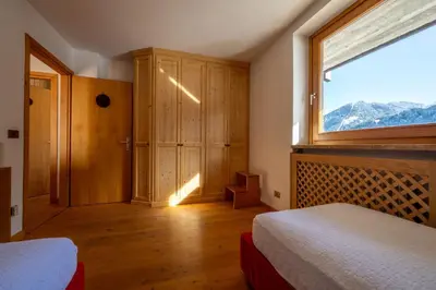 a bedroom with a large window and a bed at Cesa Azola in Vigo di Fassa